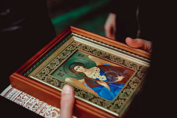 Photo of a woman holds an Orthodox icon of the guardian angel in her hands