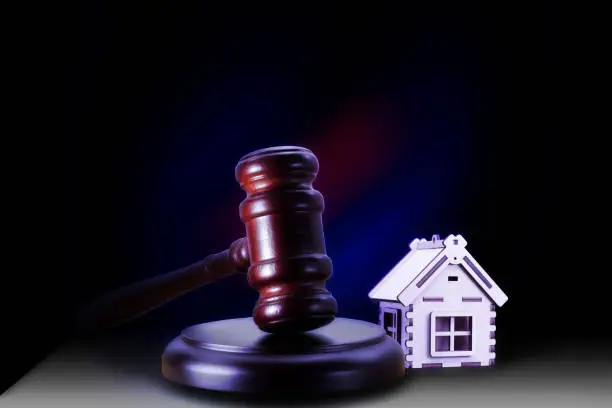 Photo of Abstract photo with wooden gavel and abstract house as symbol of sale of mortgage or emergency housing at auction