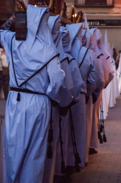 In the street, a group of brotherhood bearers carry on their shoulders the platform with the image of Jesus Christ, the men with their faces covered under hoods.