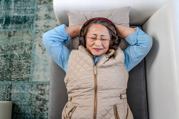 Relaxed Senior Woman lying on couch after work Relaxed Senior Woman lying on couch after work headphones plugged in photos stock pictures, royalty-free photos & images