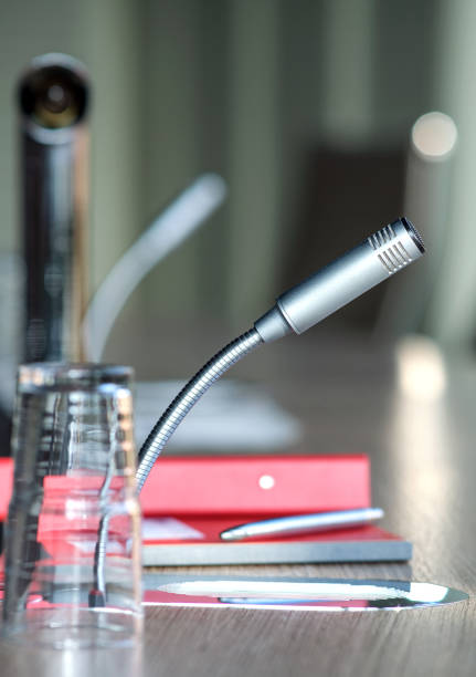 communication, media and news concept: close-up of a microphone on a table in an office, conference hall or meeting room with notebook, sheets, documents, files and writing materials - newspaper blank business the media imagens e fotografias de stock