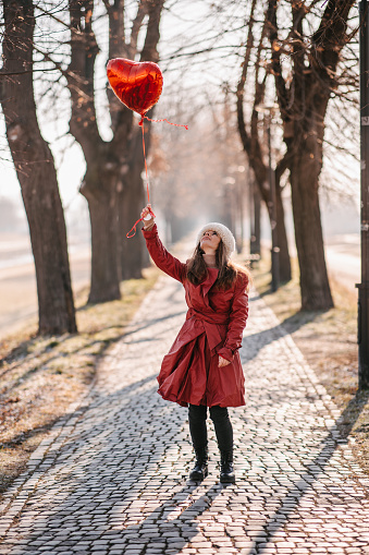 Woman holding hot air heart balloon on a cold winter’s morning. Valentine’s day concept