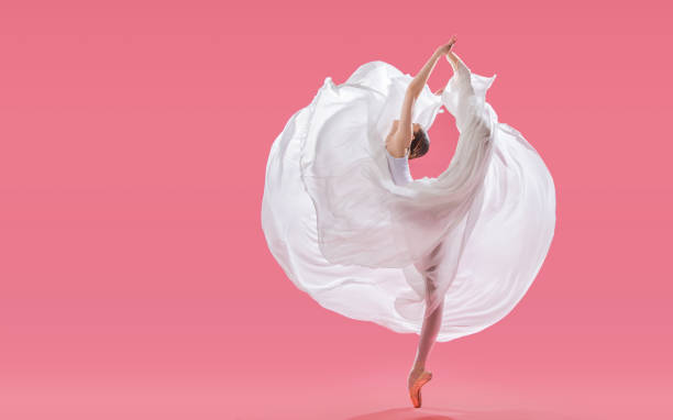 bailarina elegante em sapatos pointe dançando em uma saia longa branca em um fundo rosa - round bale - fotografias e filmes do acervo