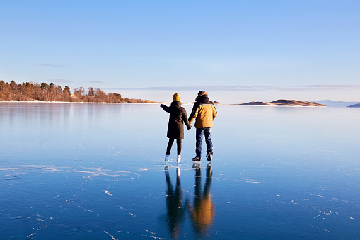 Una joven pareja está patinando en el congelado lago Baikal. Hielo transparente. photo