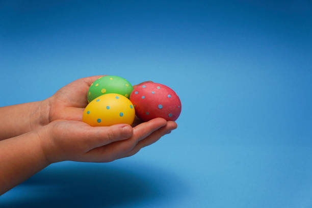 istock Easter pastel colored eggs in kids hands on light blue background. Symbolizes love, faith and hope. Easter card. Easter Nature concept. Minimal concept. Copyspace. 1366768151
