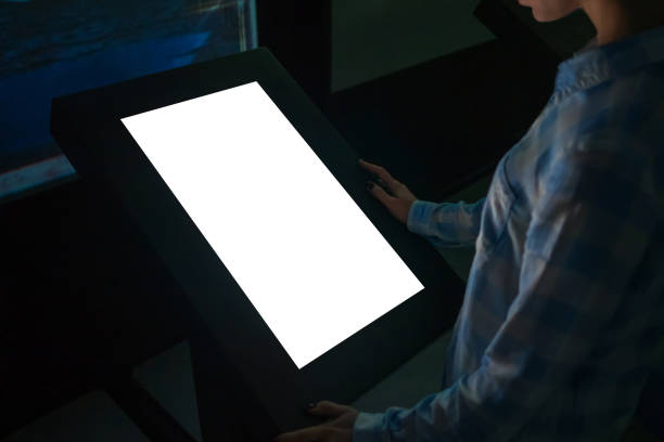istock Mockup image - woman looking at white blank touchscreen display kiosk 1366768227