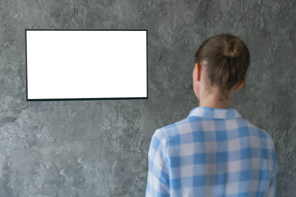 istock Woman watching flat smart led TV with white blank screen - mockup concept 1366768409