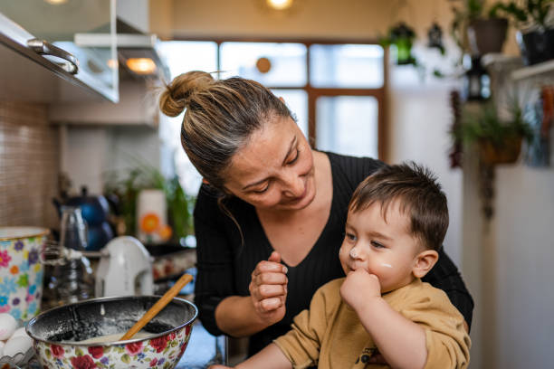 Baby sitter and baby boy having fun in the kitchen while making a cake stock photo