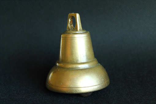 Metal heavy old bronze bell. Close-up. Isolated object on a black background.