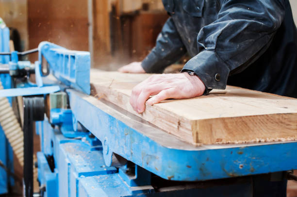 istock Carpenter plans a board in a carpentry workshop on a large stationary machine close-up 1366771812