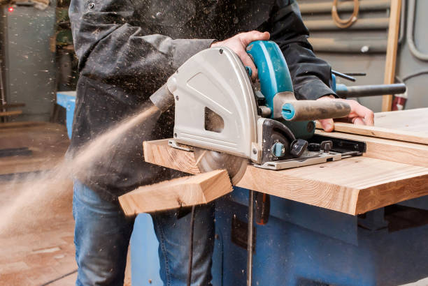 istock Male carpenter sawing a board with a circular saw in a carpentry workshop close-up 1366771853