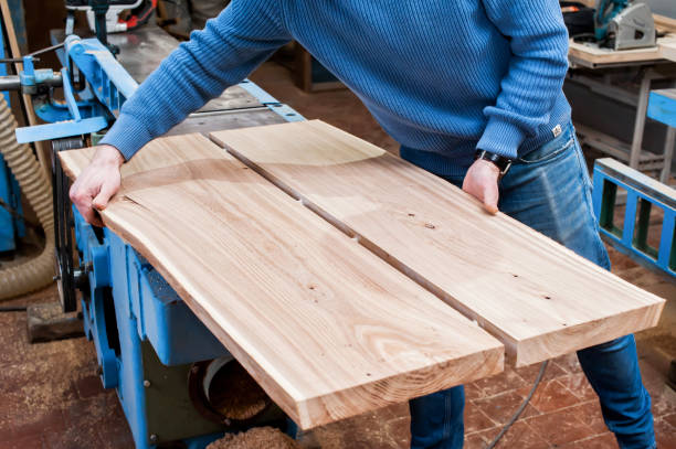 istock Male carpenter glues two boards in a carpentry workshop. Dowel and adhesive connection. Manufacture of furniture boards and countertops 1366771894