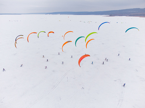 SnowKiting kitesurfing sport on the ice lake winter. Aerial drone shot.