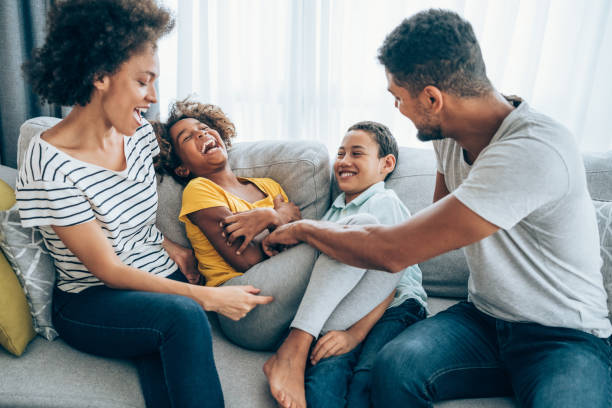 Happy family at home. Cheerful parents having fun while tickling their two kids on sofa in the living room. 9 stock pictures, royalty-free photos & images