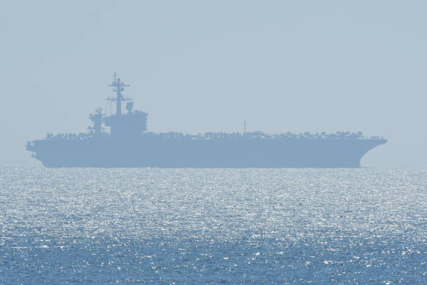 US Navy aircraft carrier sailing on the horizon.
