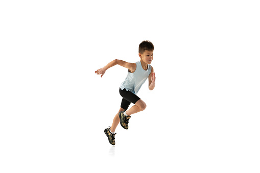 Side view studio portrait of boy, teenager in motion, running isolated over white background. Concept of action, sport, healthy life, competition, motion, physical activity. Copy space for ad