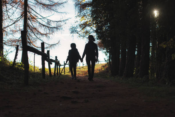 Mom and son walk hand in hand in a forest during a hike