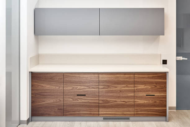 Contemporary kitchen furniture set in minimalist style of walnut wood and gray color with acrylic solid surface countertop in office close-up