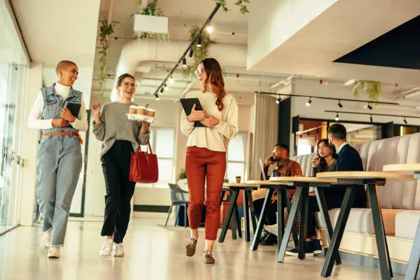 Photo of Three businesswomen walking through an office in the morning