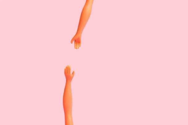 istock Two doll hands trying to catch each other on a pink background 1366783968