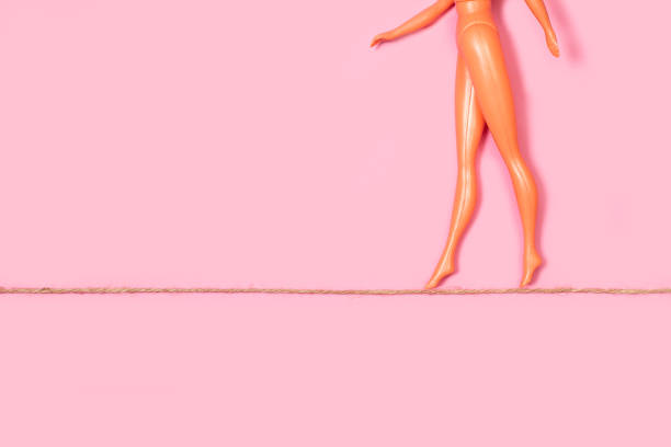 poupée nue marchant sur une corde sur fond rose - mannequin naked female doll photos et images de collection