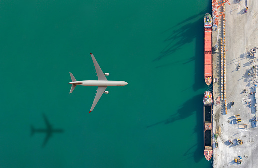Airplane above cargo ship.