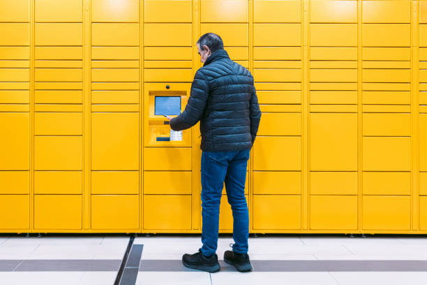 istock Man from behind scans a code on the mobile phone to pick up a package from the yellow locker. Messaging concept, compare online, e-commerce and packages 1366786406