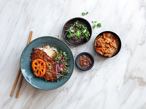 Korean BBQ pork ribs with rice. Flat lay top-down composition on marble background.