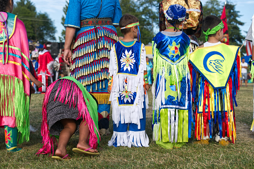 This Powwow was celebrated on the Capilano Reserve, West Vancouver, British Columbia, Canada on 8 July, 2017. The Squamish Nation's 30th Annual Powwow was a gathering of First Nations communities to honour their culture, share, respect, dance and drum. Their heritage is respected by all ages. Children and a jingle dancer, waiting to dance.