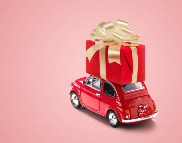 istock Red toy car with gift box on a roof on pink background. Copy space. 1366792441