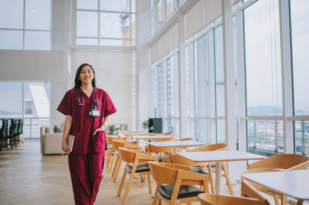 asian chinese female nursecafeteri smiling walking at cafeteria of hospital asian chinese female doctor smiling walking at corridor of hospital red medical scrubs stock pictures, royalty-free photos & images