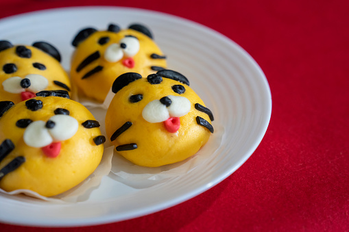 Steamed buns decorated to look like a tiger placed on a plate on red cloth, to commemorate Lunar New Year in 2022, which is the Year of the Tiger in the Chinese Zodiac.