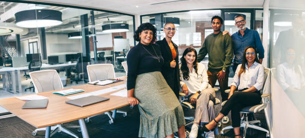 team of businesspeople smiling at the camera in a boardroom - work stockfoto's en -beelden