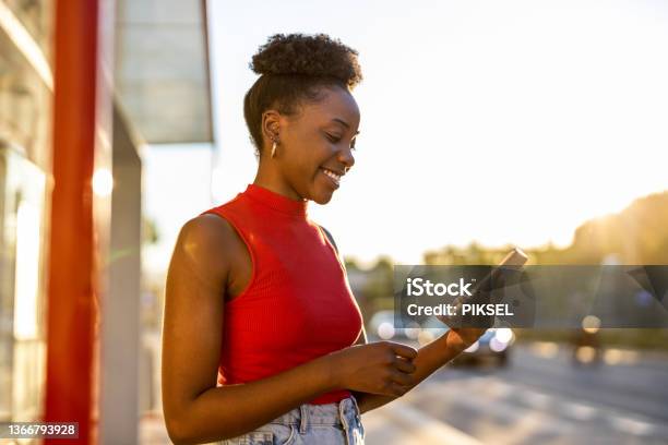 Young Woman With Smartphone Waiting At The Bus Stop Stock Photo - Download Image Now