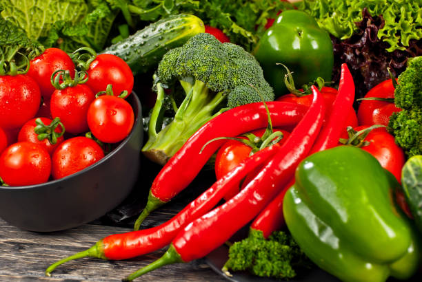 istock Cabbage, peppers, tomatoes, cucumbers, lettuce, cherry tomatoes, broccoli, arugula on a black background. variety of vegetables on a pile on a wooden table. 1366794113