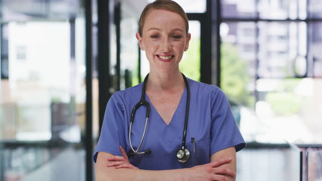 4k video footage of an attractive young nurse standing alone in the clinic with her arms folded