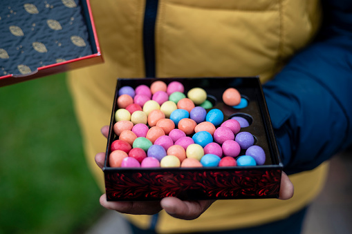 Close up of a colourful box of chocolates on Easter. The unrecognisable man is holding them outdoors in the North East of England.