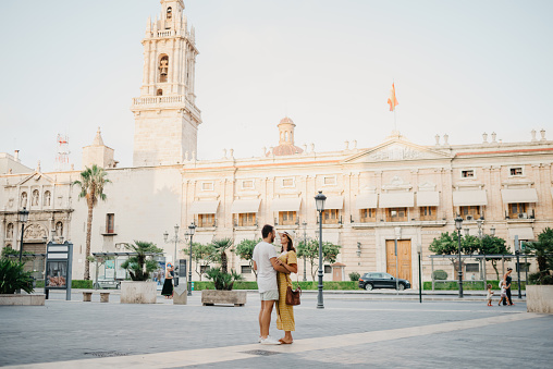 A girl in a hat and a dress is dancing with a boyfriend with a beard in Valencia
