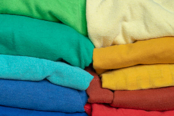 istock Stacks of multicolored fabrics in cool and warm colors are compared next to each other. Background with folded clothes with blank space for information. T-shirts of different colors 1366798269