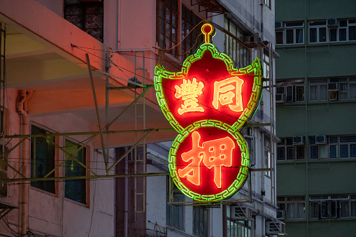 Hong Kong - January 25, 2022 : Pawn shop sign in Wan Chai, Hong Kong. The iconic neon green and red signs can be seen in most of Hong Kong's 18 districts, they are some of the oldest businesses in Hong Kong.