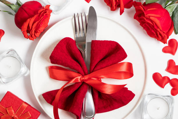 Table setting for valentine's day. Red roses and cutlery on a white background.
