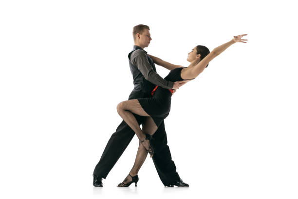 istock Dynamic portrait of flexible young dancers dancing Argentine tango isolated on white studio background. Artists in black stage costumes 1366800031