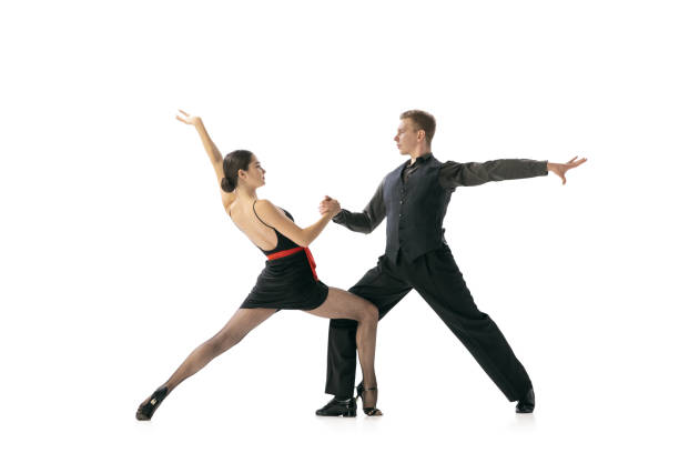 istock Flexible young couple dancing Argentine tango isolated on white studio background. Artists in black stage costumes 1366800057