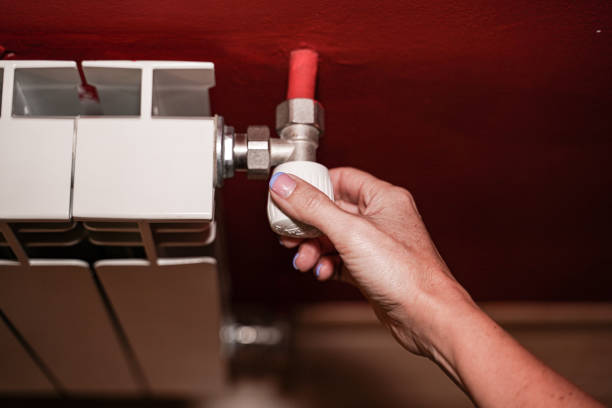 istock Person activating thermostat to regulate a water radiator located on a wall. 1366801201