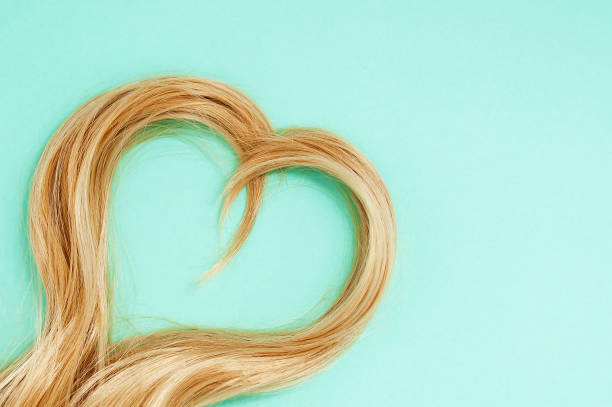 Blonde strands of hair in the shape of heart. Green background. Blonde strands of hair in the shape of a heart. Green background. hair strands stock pictures, royalty-free photos & images