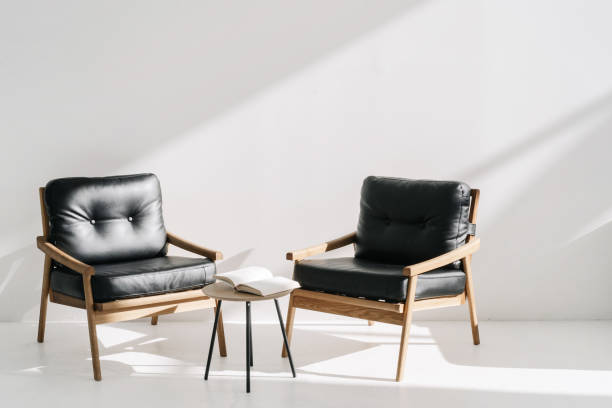 Two leather armchairs standing near coffee table Two minimalistic leather armchairs standing near coffee table in luxury office or bright stylish apartment. Open book, agenda or planner in meeting room at business center dresser domestic room entrance hall home interior stock pictures, royalty-free photos & images