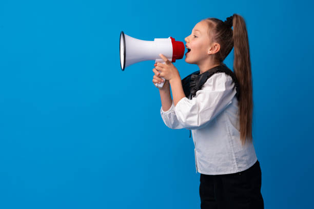 istock Child girl using megaphone against blue background 1366806105