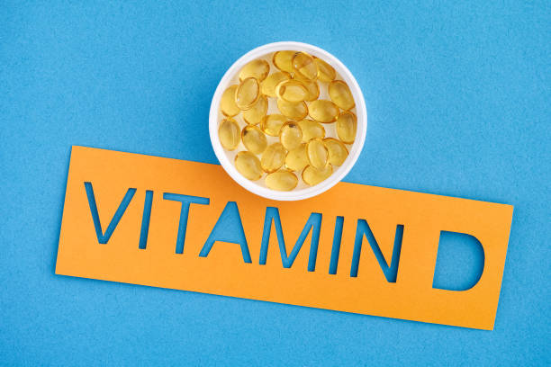 The word Vitamin D with a small cup of Vitamin D3 capsules on it The word Vitamin D with a small cup of Vitamin D3 capsules on it. Close up. vitamin d stock pictures, royalty-free photos & images