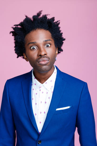 Portrait of shocked elegant man Angry afro american man wearing navy blue jacket and white shirt staring at camera. Studio shot on pink background. Portrait of designer. rolling eyes irritation displeased facial expression stock pictures, royalty-free photos & images