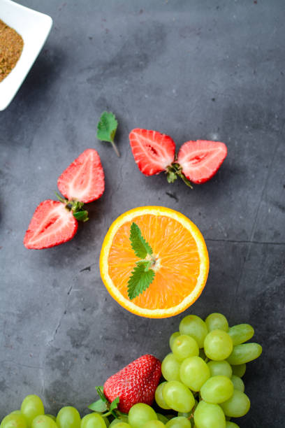 Close up strawberry photo with bananas in the background, blueberries and blackberries on the foreground blurry, vertical image.
